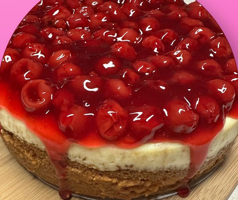 Plain cheesecake topped with glossy cherry topping on a graham cracker crust