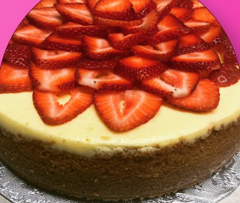 Cheesecake topped with fresh sliced strawberries arranged in a flower